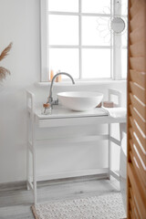 Interior of bathroom with ceramic sink and reed diffuser near window