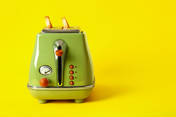 Modern toaster with crispy bread slices on yellow background