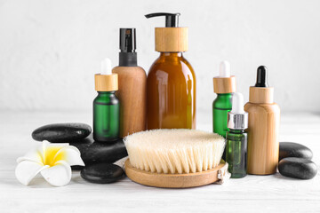 Set of cosmetic products, massage brush and spa stones on light wooden table
