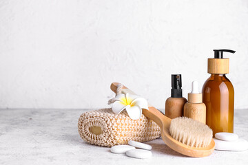 Bath supplies and bottles of cosmetic products on light background