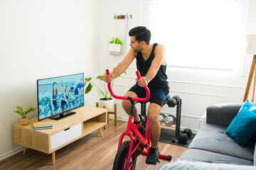 Happy fit man watching a workout video riding his stationary bike