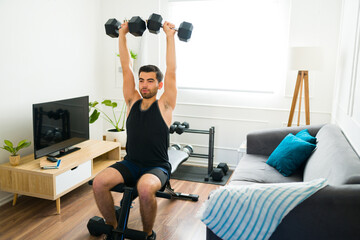 Fototapeta na wymiar Sporty young man lifting weights in the living room