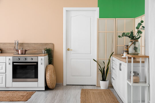 Interior of modern kitchen with white counters and electric oven