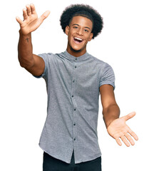 African american man with afro hair wearing casual clothes looking at the camera smiling with open arms for hug. cheerful expression embracing happiness.
