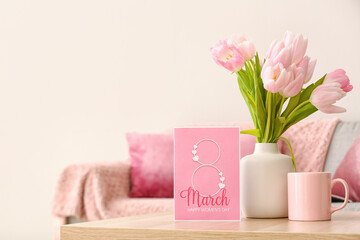 Obraz na płótnie Canvas Vase with tulips, cup and greeting card for Women's Day on table in living room