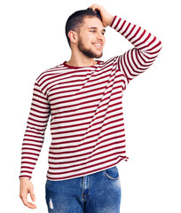 Obraz premium Young handsome man wearing striped sweater smiling confident touching hair with hand up gesture, posing attractive and fashionable