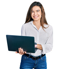 Young caucasian girl holding laptop looking positive and happy standing and smiling with a...