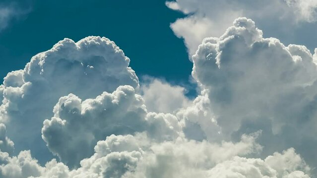 Timelapse of white puffy cumulus clouds forming on summer blue sky. Moving and changing cloudscape weather