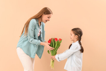 Cute little girl greeting her mother with tulips on beige background