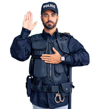Young hispanic man wearing police uniform swearing with hand on chest and open palm, making a loyalty promise oath