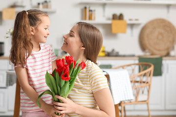 Fototapeta na wymiar Cute little girl and her mother with tulips in kitchen