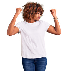 Young african american woman wearing casual white tshirt showing arms muscles smiling proud. fitness concept. - obrazy, fototapety, plakaty