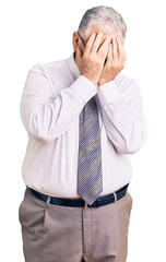 Senior grey-haired man wearing business clothes with sad expression covering face with hands while crying. depression concept.