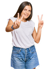 Young caucasian woman wearing casual white tshirt smiling looking to the camera showing fingers doing victory sign. number two.