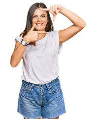Fototapeta premium Young caucasian woman wearing casual white tshirt smiling making frame with hands and fingers with happy face. creativity and photography concept.