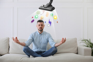 Purification of mind. Vacuum cleaner extracting bad thoughts from meditating man on sofa indoors