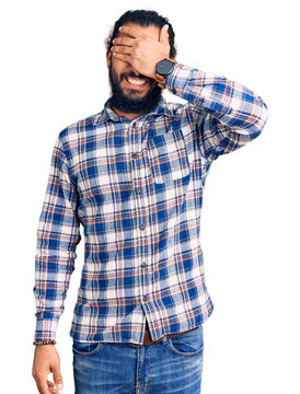 Young arab man wearing casual clothes smiling and laughing with hand on face covering eyes for surprise. blind concept.