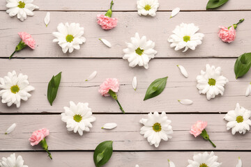 Composition with beautiful flowers and plant leaves on light wooden background