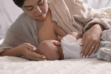 Fototapeta na wymiar Mother breastfeeding her newborn baby on bed, closeup