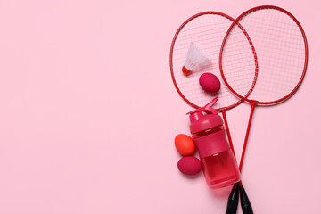 Badminton rackets, shuttlecock, water bottle and Easter eggs on pink background