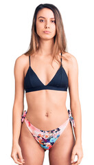 Fototapeta premium Young beautiful girl wearing bikini with serious expression on face. simple and natural looking at the camera.
