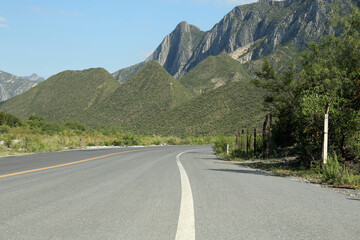 Beautiful view of empty asphalt highway near mountains outdoors. Road trip