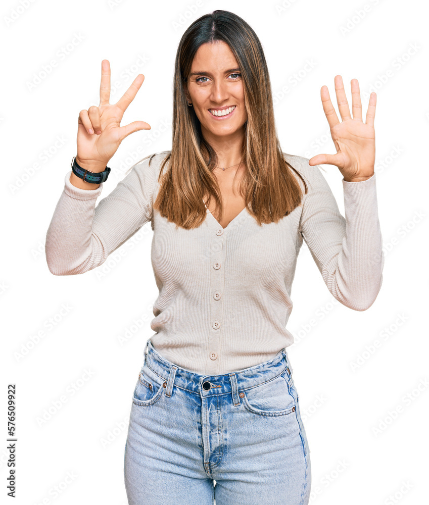 Wall mural Young woman wearing casual clothes showing and pointing up with fingers number eight while smiling confident and happy.