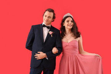 Beautiful couple dressed for prom on red background
