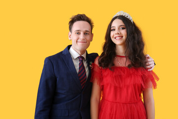 Beautiful couple dressed for prom on yellow background