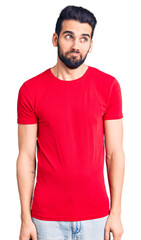 Fototapeta premium Young handsome man with beard wearing casual t-shirt smiling looking to the side and staring away thinking.