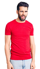 Obraz premium Young handsome man with beard wearing casual t-shirt winking looking at the camera with sexy expression, cheerful and happy face.