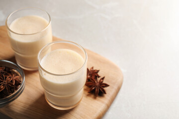 Glasses of delicious eggnog with anise on grey marble table. Space for text