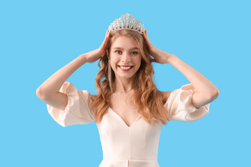 Teenage girl in tiara and prom dress on blue background © Pixel-Shot