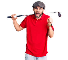 Young handsome man with beard playing golf holding club and ball screaming proud, celebrating victory and success very excited with raised arms
