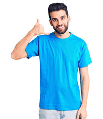 Young handsome man with beard wearing casual t-shirt smiling doing phone gesture with hand and fingers like talking on the telephone. communicating concepts.