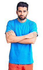 Young handsome man with beard wearing casual t-shirt skeptic and nervous, disapproving expression on face with crossed arms. negative person.