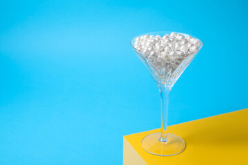 Beautiful martini glass with pearls on light blue background. Space for text