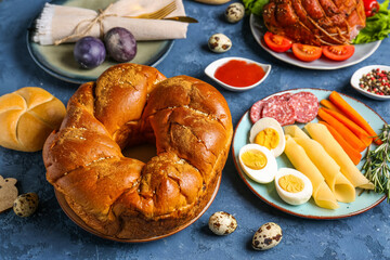 Tasty dishes for Easter dinner and eggs on color background