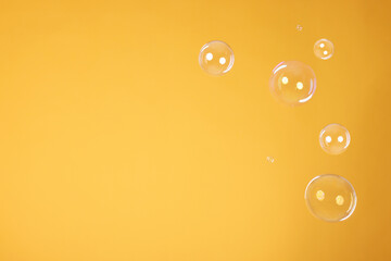 Many beautiful soap bubbles on orange background. Space for text