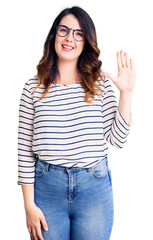Beautiful young brunette woman wearing casual clothes and glasses showing and pointing up with fingers number five while smiling confident and happy.