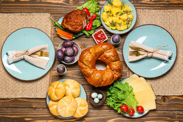 Tasty dishes and painted eggs for Easter dinner on wooden background