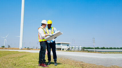 Low angle view of Architectural engineer teamwork people working his blueprints discussing renewable wind turbine generate electricity to produce energy with copy space.