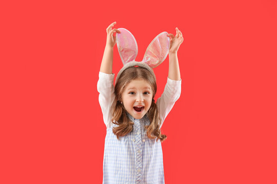 Cute little girl in bunny ears on red background