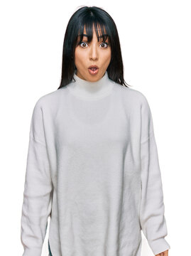 Young brunette woman with bangs wearing casual turtleneck sweater afraid and shocked with surprise expression, fear and excited face.
