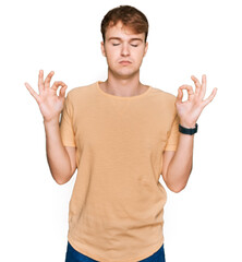 Young caucasian man wearing casual clothes relaxed and smiling with eyes closed doing meditation gesture with fingers. yoga concept.