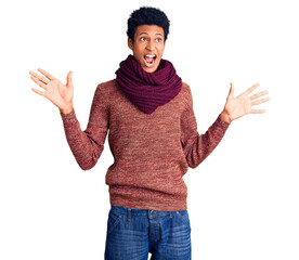Young african american man wearing casual winter sweater and scarf celebrating crazy and amazed for success with arms raised and open eyes screaming excited. winner concept