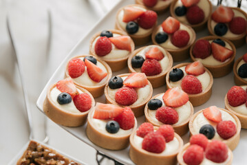 platter of mini strawberry and blueberry fruit tartlets on rectangular white platter