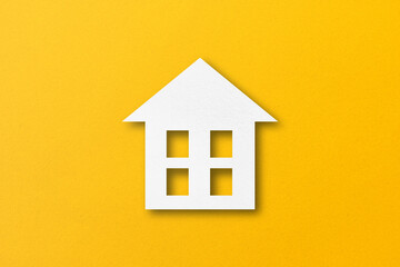 Fototapeta na wymiar White paper cut out house shape isolated on yellow paper background.