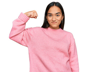 Young asian woman wearing casual winter sweater strong person showing arm muscle, confident and...