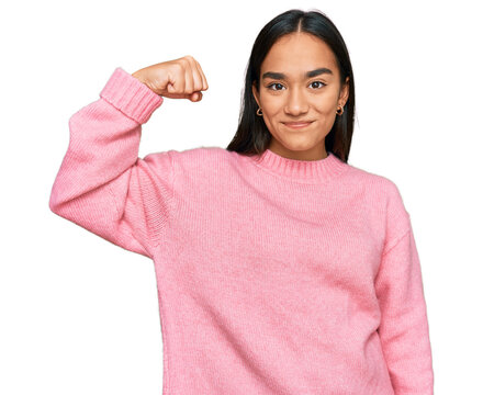 Young asian woman wearing casual winter sweater strong person showing arm muscle, confident and proud of power